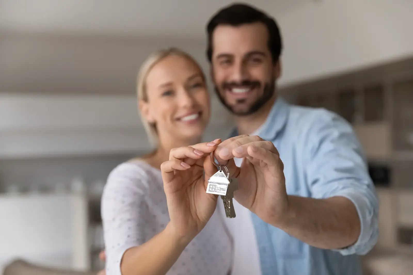 Couple holding house keys toward the camera after closing